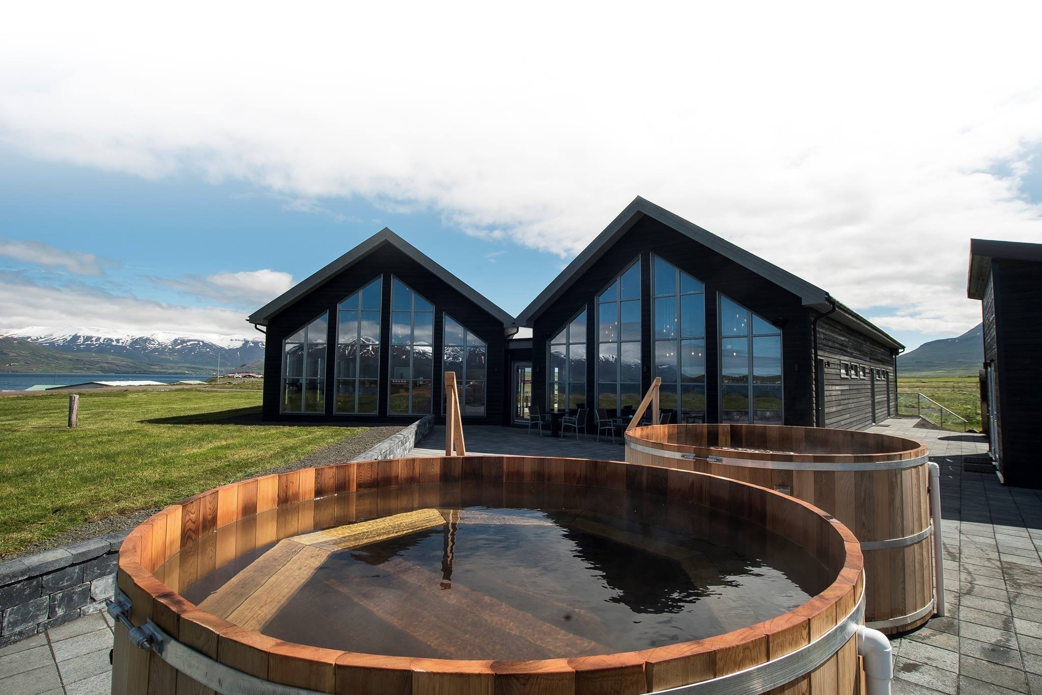 Outdoor wooden tubs at Bjórböðin with Eyjafjörður and mountains behind