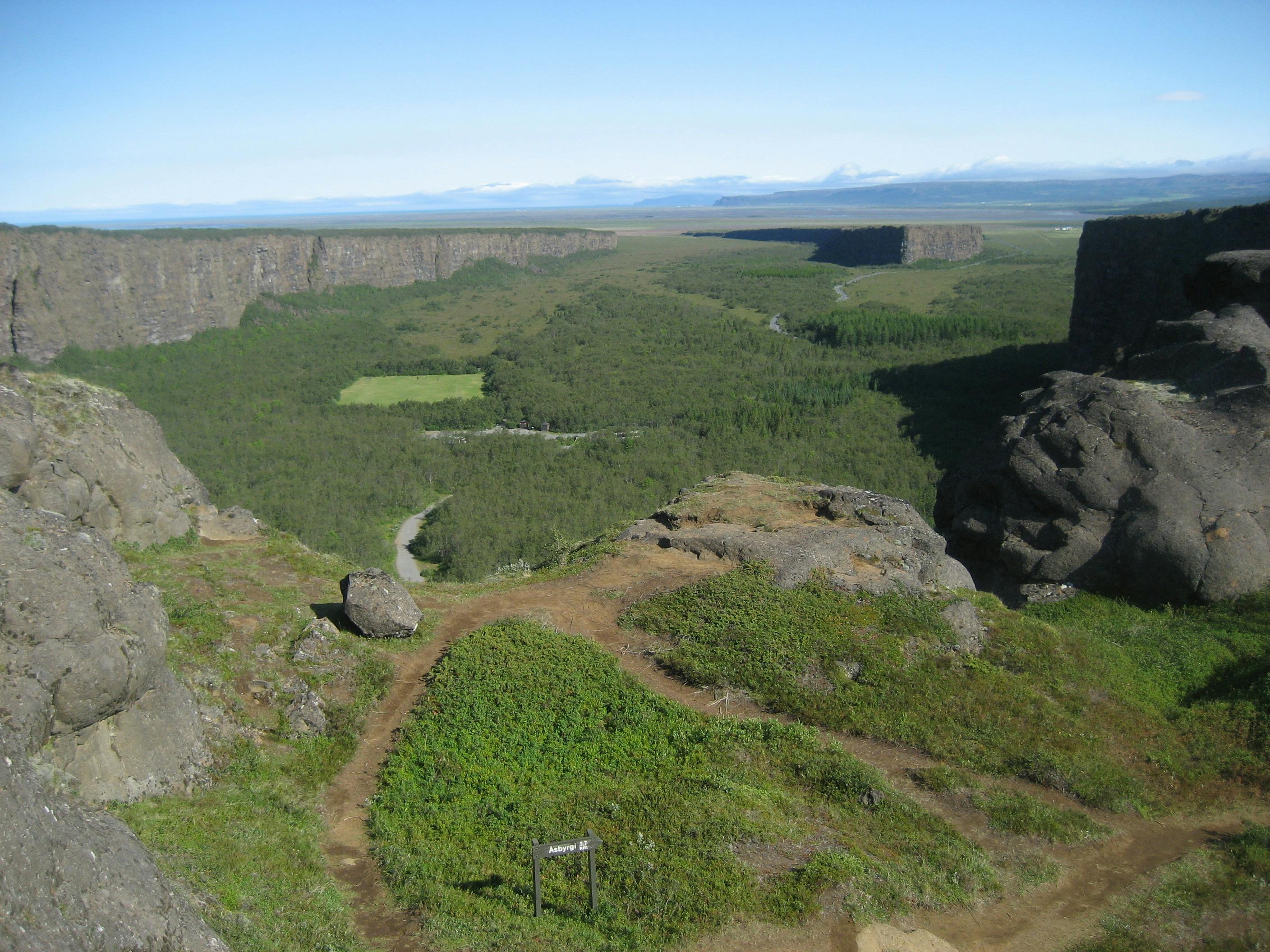 Wide view over Ásbyrgi canyon from Klappir with green woodland between high rock walls.