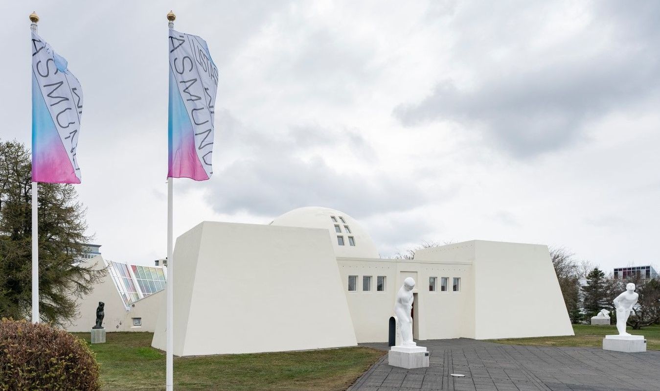 Ásmundarsafn exterior with museum flags, white walls, and sculptures near the entrance.