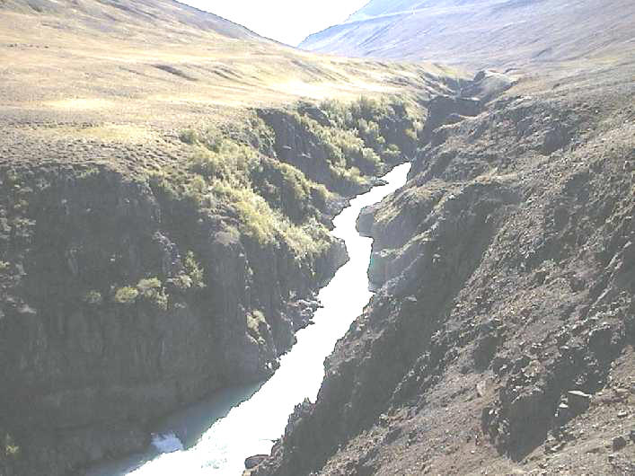 Narrow Austurdalur gorge with the Austari-Jökulsá river below grassy slopes.