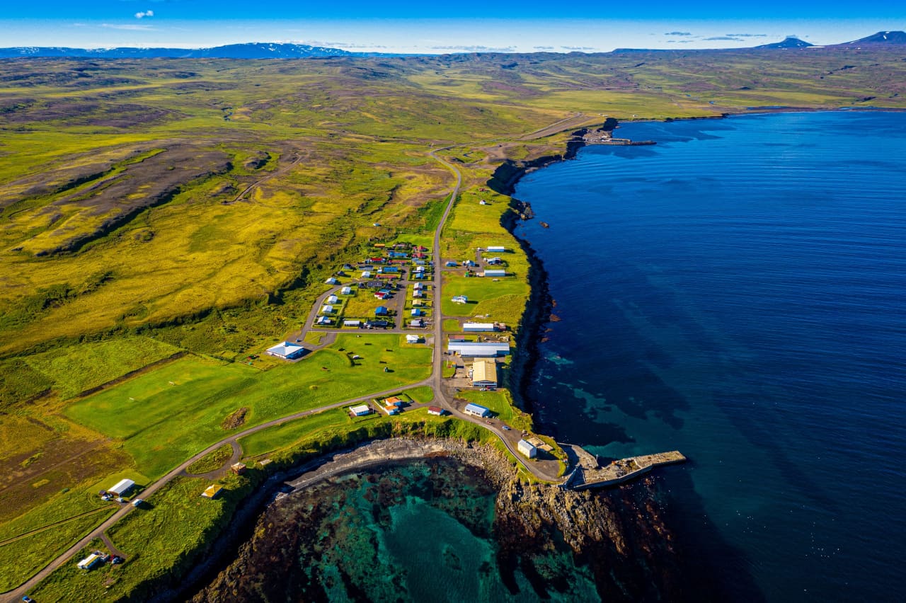 Aerial view of Bakkafjörður with the old harbor, curved shoreline, and open bay around the small village.