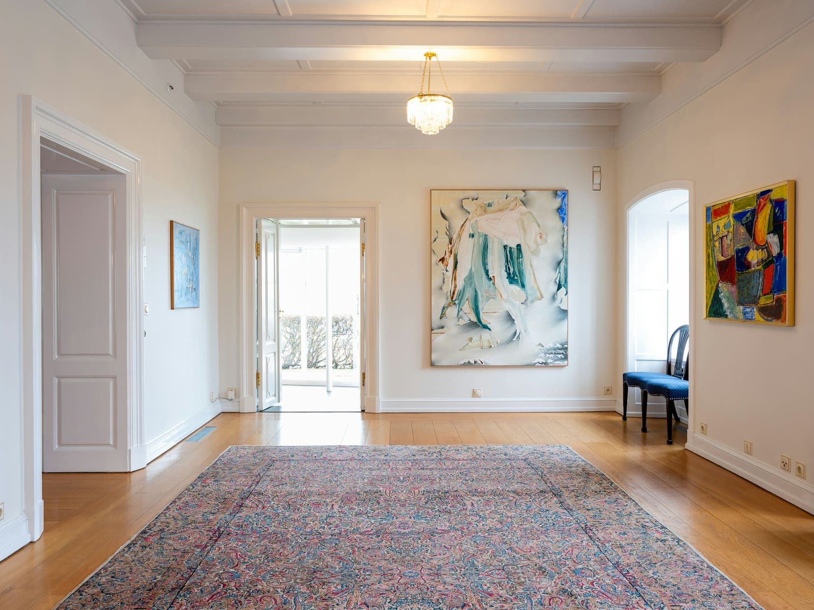 Art-filled room inside Bessastaðir with white walls, paintings, and a patterned rug.