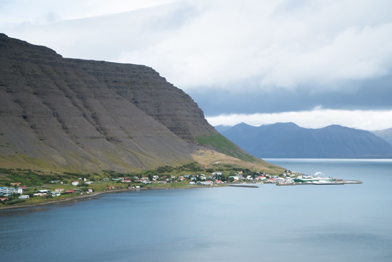 Bíldudalur village and harbor spread below layered cliffs beside Arnarfjörður.