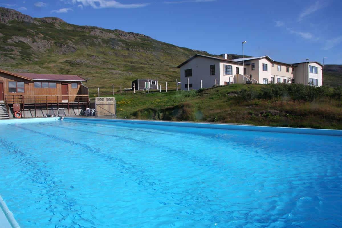 Laugarhóll pool and buildings below green hills in Bjarnarfjörður.