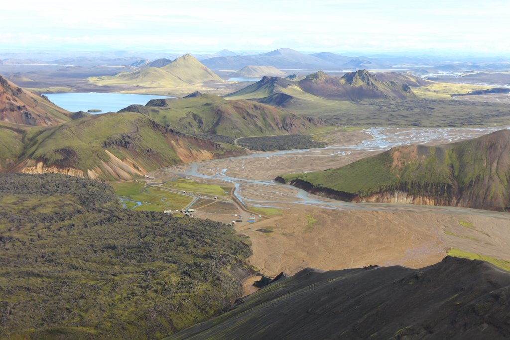 View from Bláhnjúkur over Landmannalaugar, Laugahraun lava, pale river braids, and surrounding Highlands mountains.