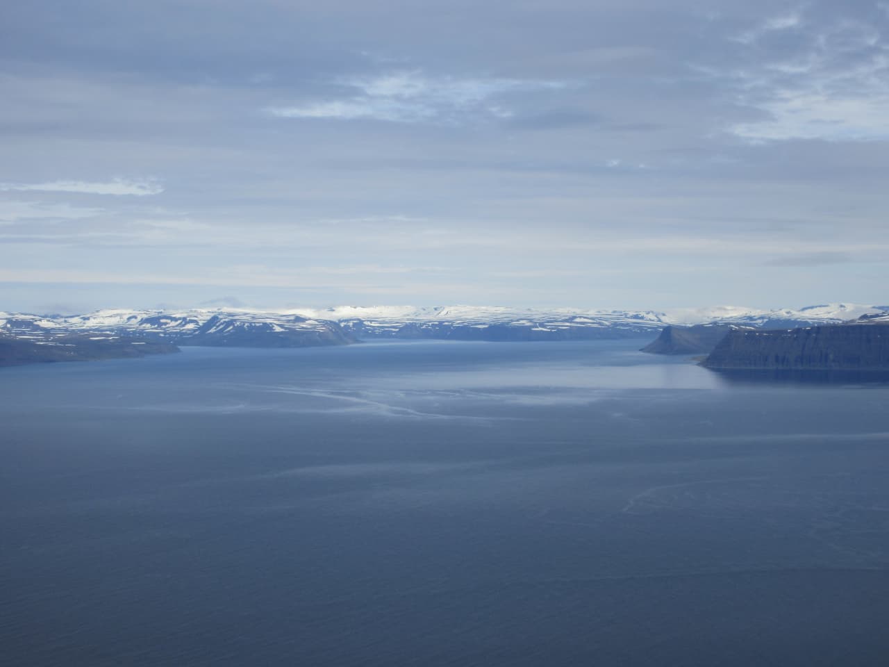 View from Bolafjall across Ísafjarðardjúp toward snow-streaked Westfjords mountains.