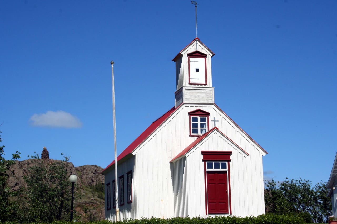 White Borg á Mýrum church with red trim under a clear blue sky