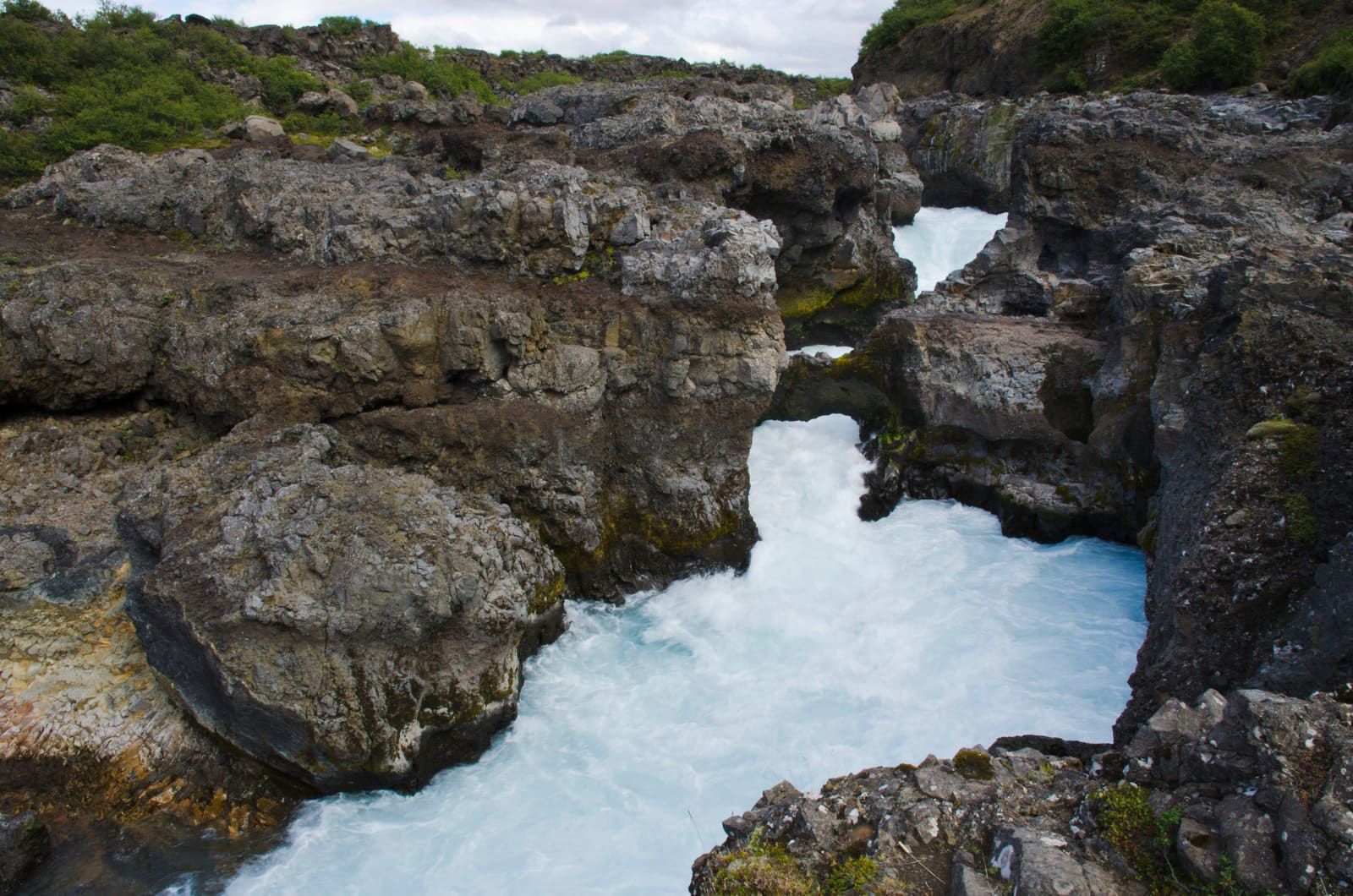 Barnafoss rushing through a dark lava-rock gorge in Borgarfjörður.