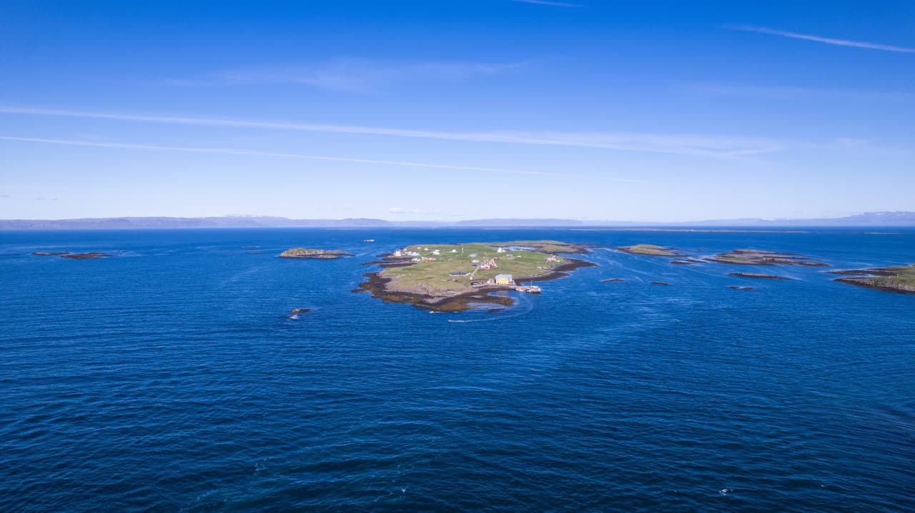 Flatey island village, low green land, and blue Breiðafjörður water seen from above.