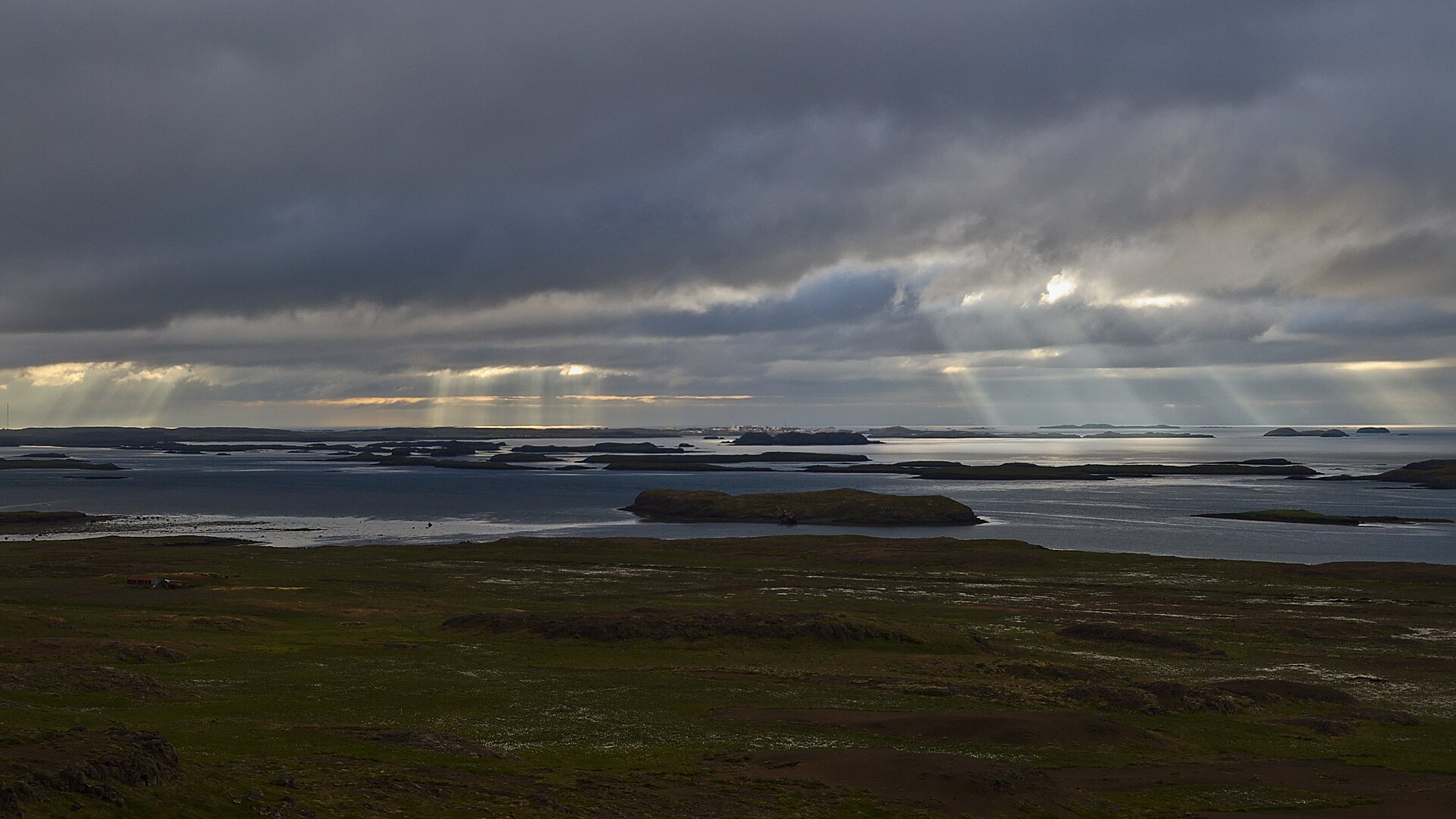 Low islands scattered across Breiðafjörður under dark clouds and shafts of light.