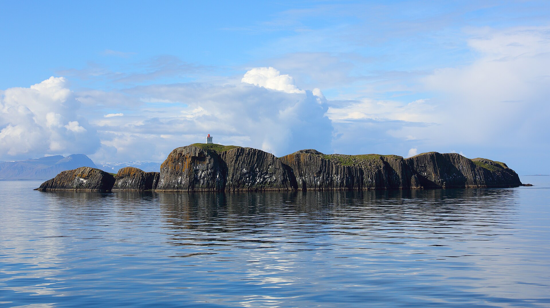 Elliðaey island lighthouse rising from dark sea cliffs in Breiðafjörður.