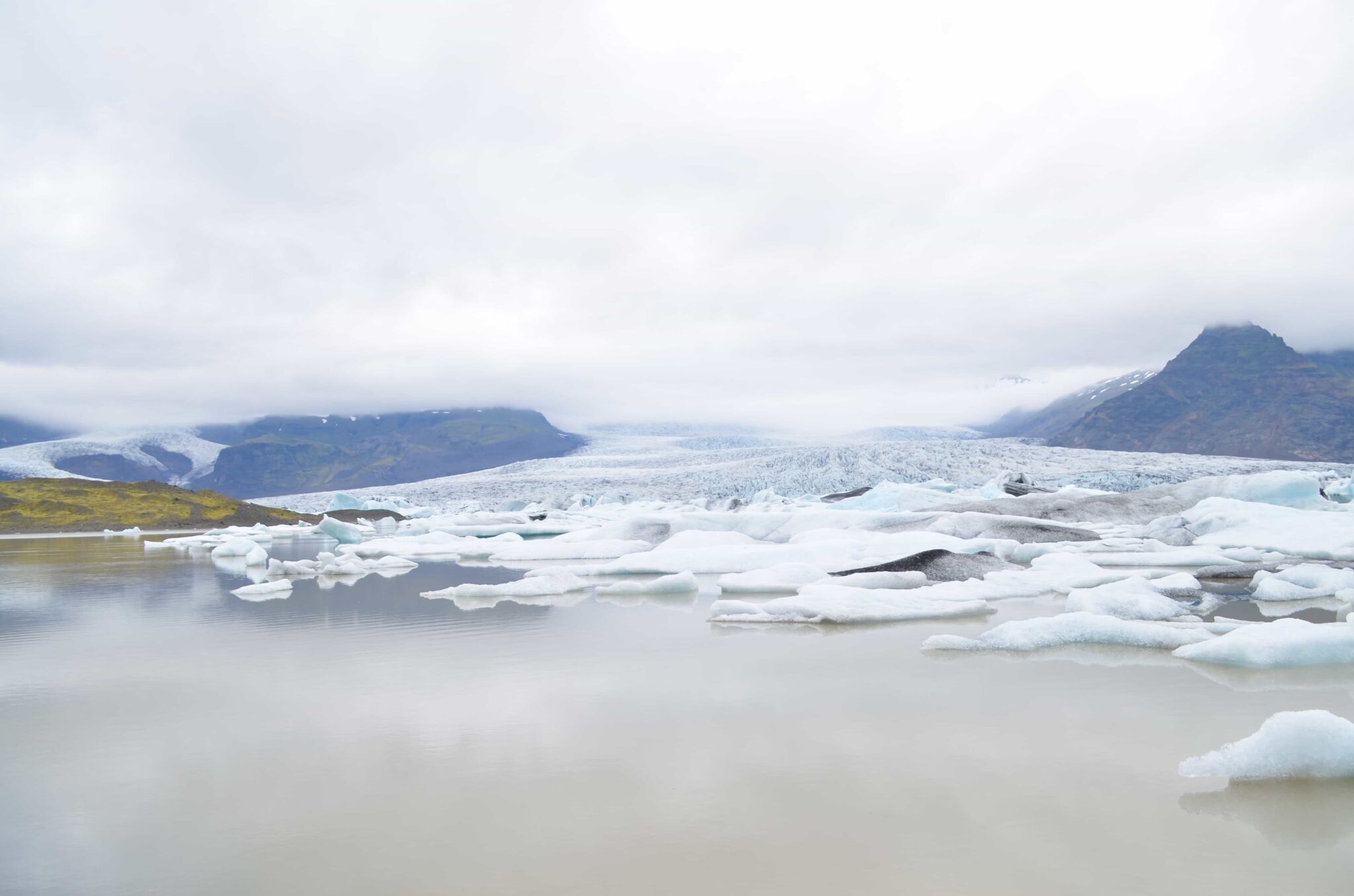 Low clouds over glacier ice and floating icebergs at Breiðárlón in southeast Iceland.