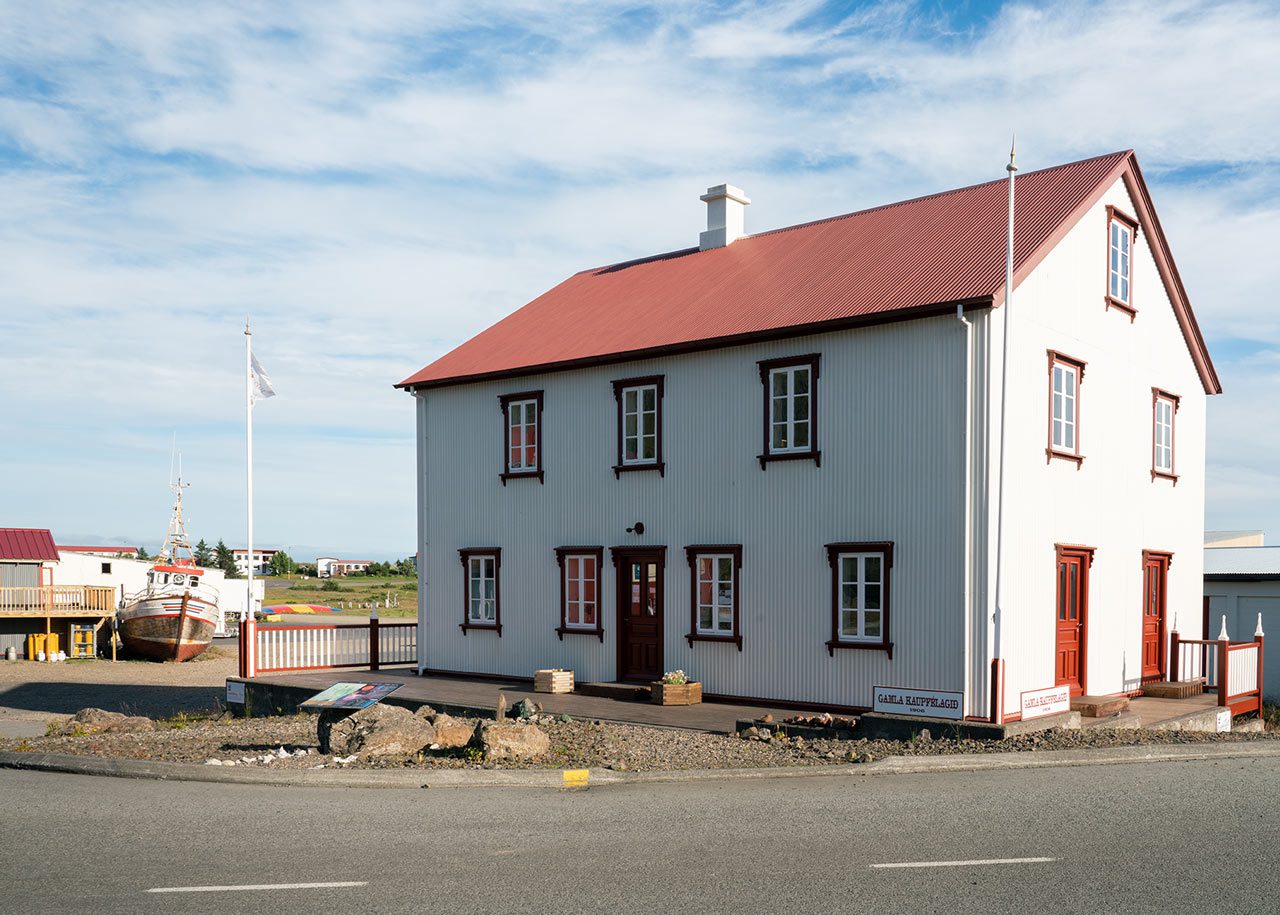 Breiðdalssetur in the old general store at Breiðdalsvík, with a red roof, white walls, and a boat nearby.
