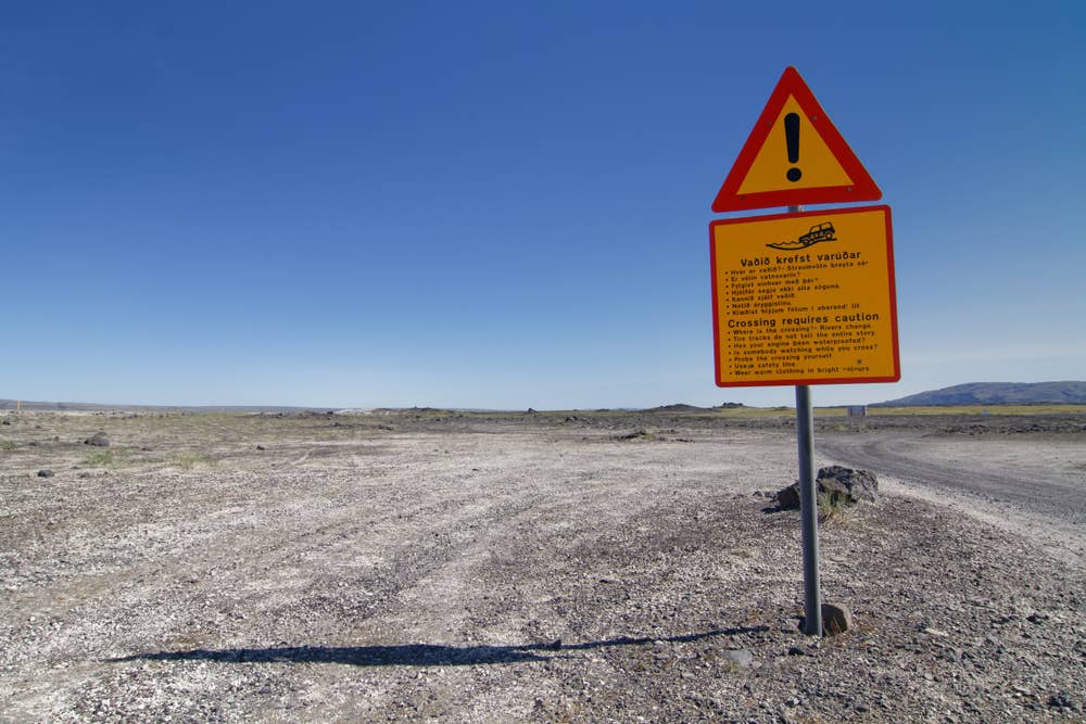 A yellow caution sign beside a gravel Highland road on the approach to Landmannalaugar.