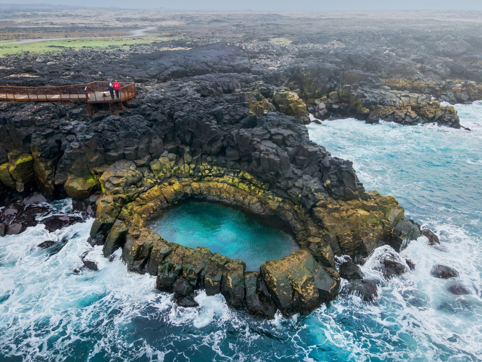 Aerial view of Brimketill with its lava rock pool, viewing platform, black shore, and Atlantic surf.