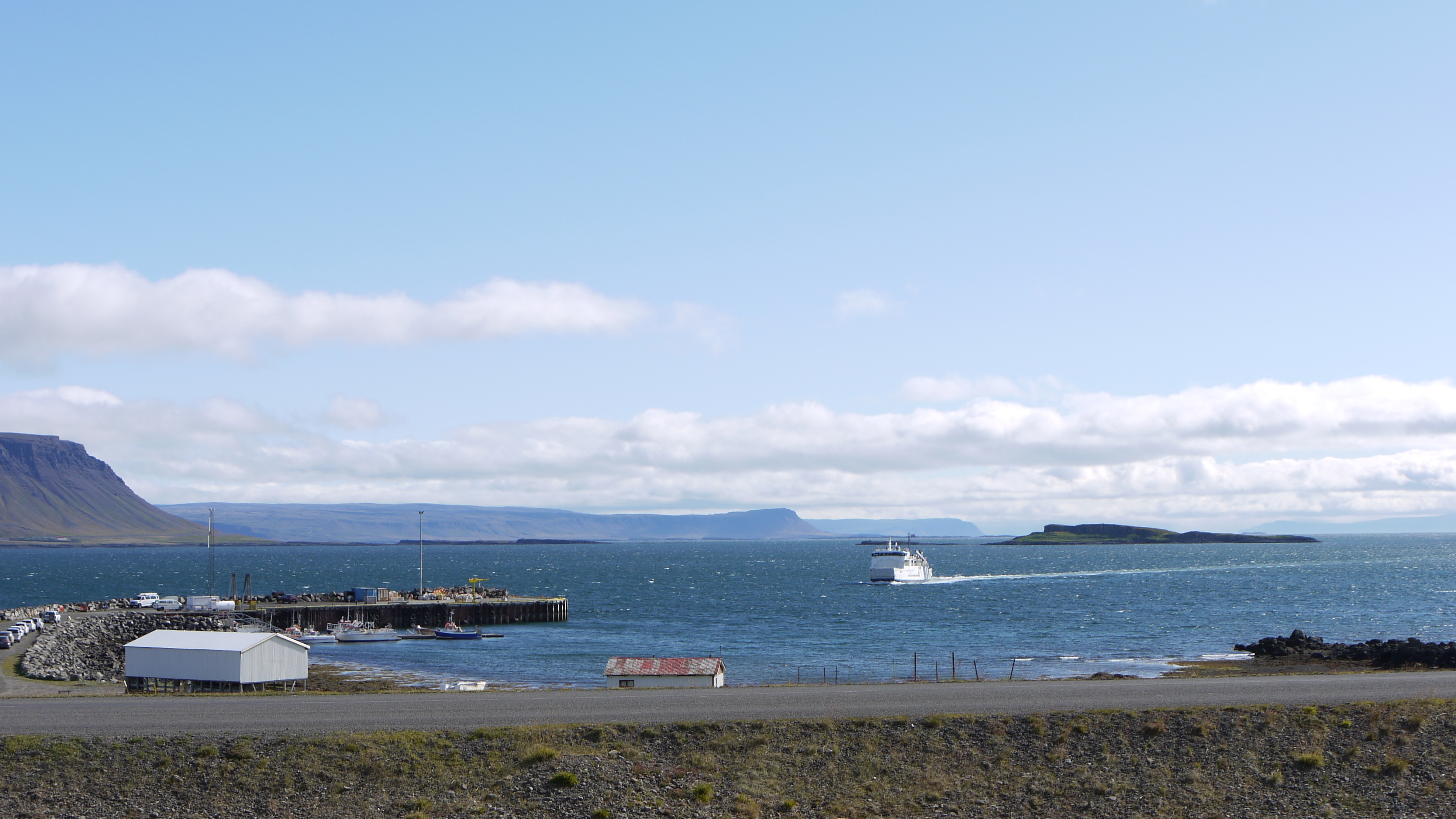 Baldur arriving beside Brjánslækur harbor with low islands and Westfjords shoreline behind it.
