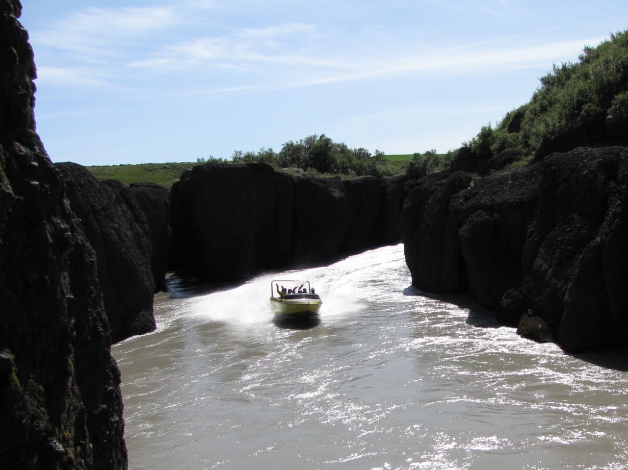 Boat moving through the narrow Brúarhlöð canyon section of the Hvítá river.