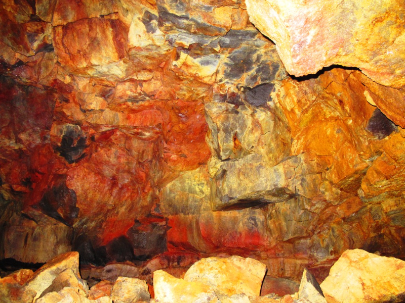 Orange, red, black, and pale lava wall textures inside Búri Lava Cave.