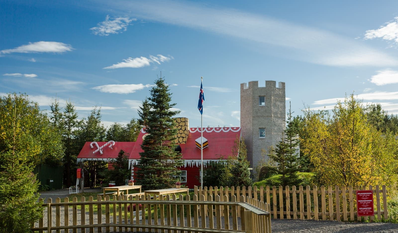 Akureyri Christmas House seen across its fenced garden with the tower and red main building behind it
