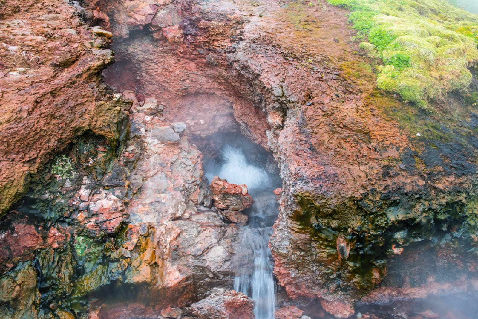 Boiling water running through red and black mineral rock at Deildartunguhver hot spring.