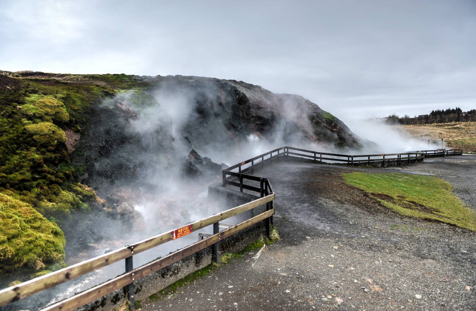 Steam drifting across hot water and low grassy ground around Deildartunguhver.