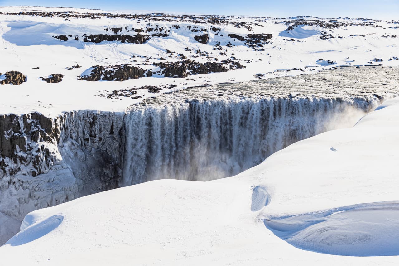 Dettifoss waterfall surrounded by deep snow in winter conditions.