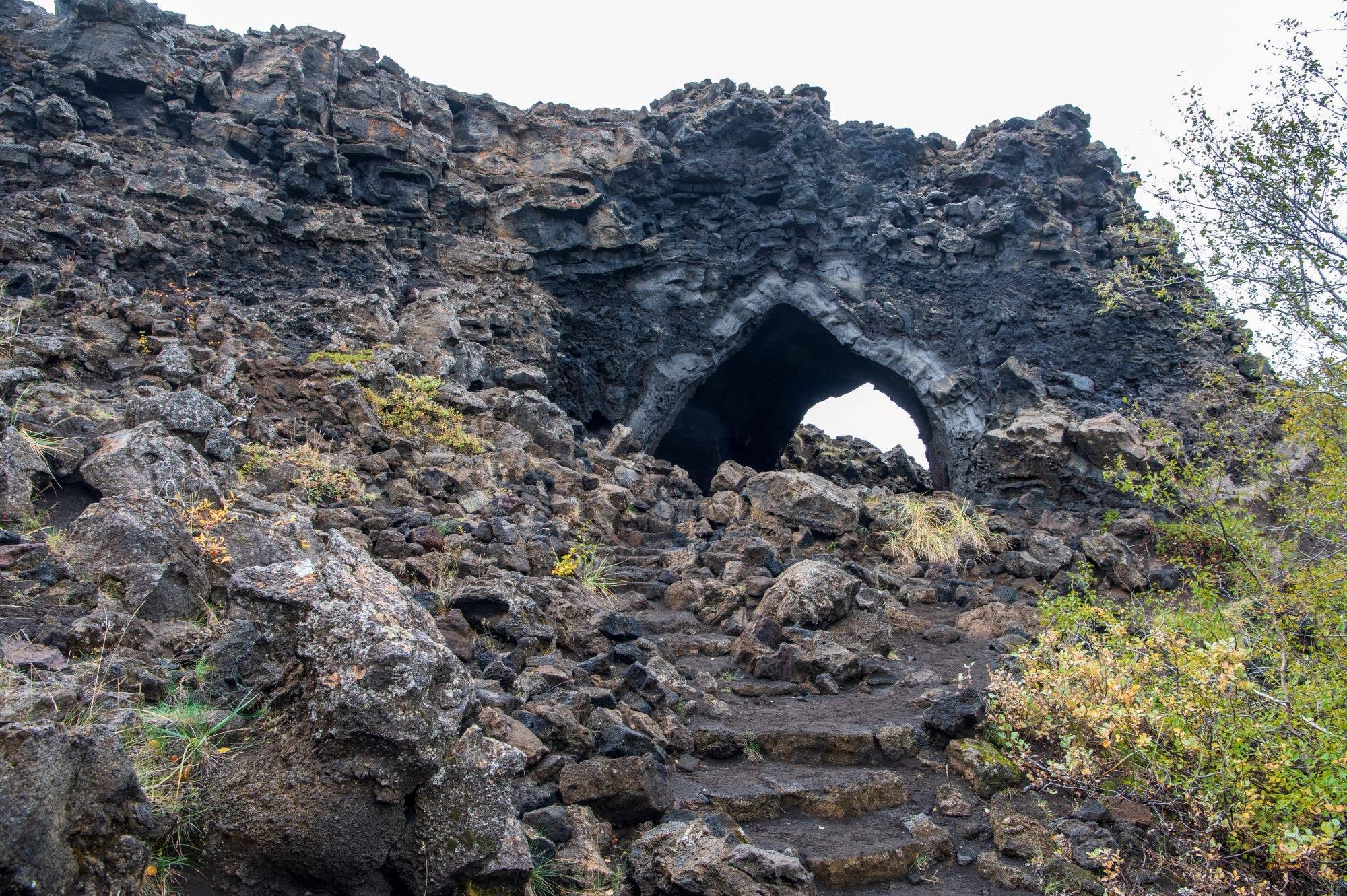 The Kirkjan lava arch at Dimmuborgir with rough rock steps leading into the dark opening.