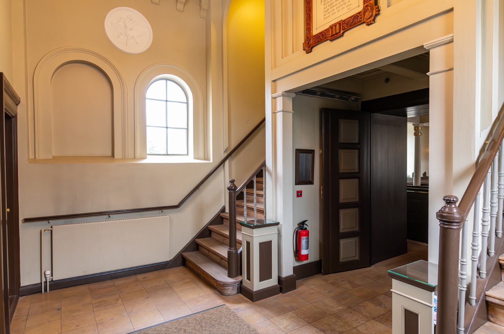 Wooden doors, stairs, and arched window inside the entrance area of Dómkirkjan