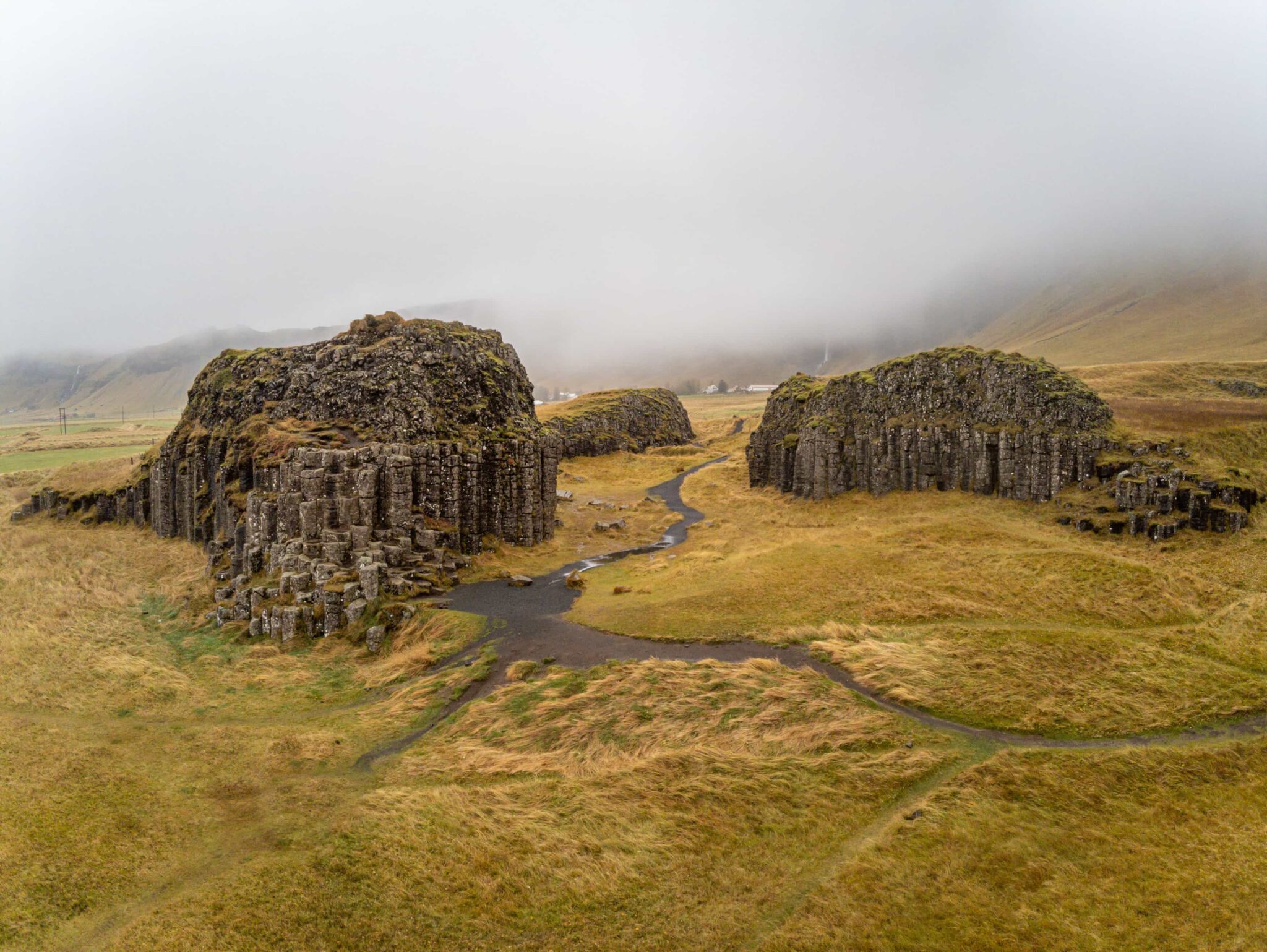 Wide view over the Dverghamrar basalt-column outcrops and walking paths in South Iceland.