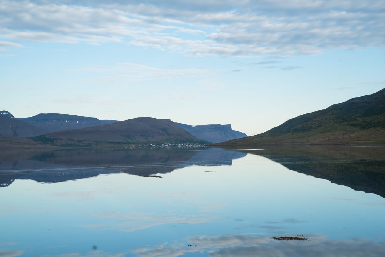 Calm water in Dýrafjörður reflecting dark Westfjords mountains near Þingeyri.