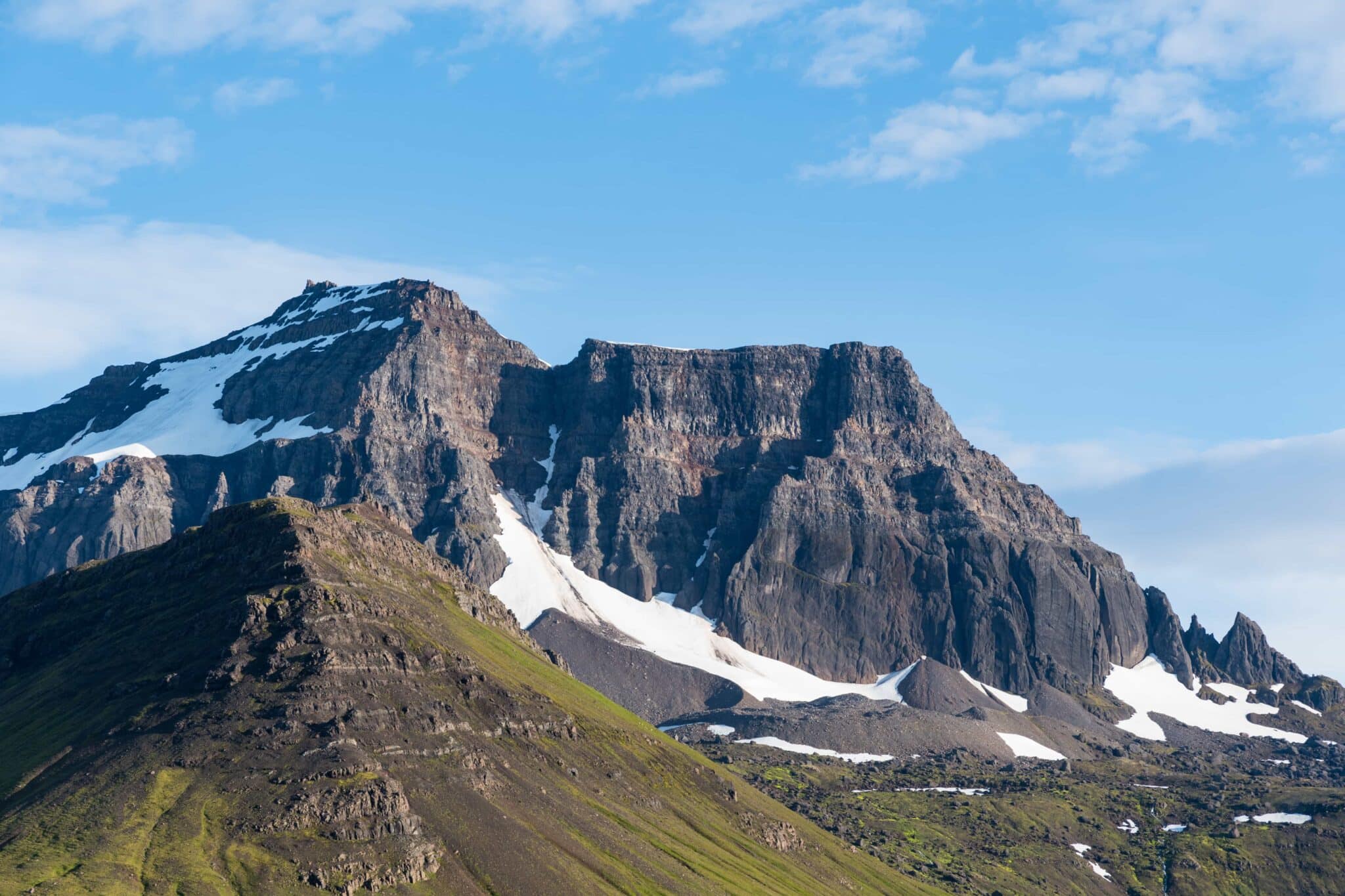 The dark ridge and snow-streaked slopes of Dyrfjöll under a blue sky.