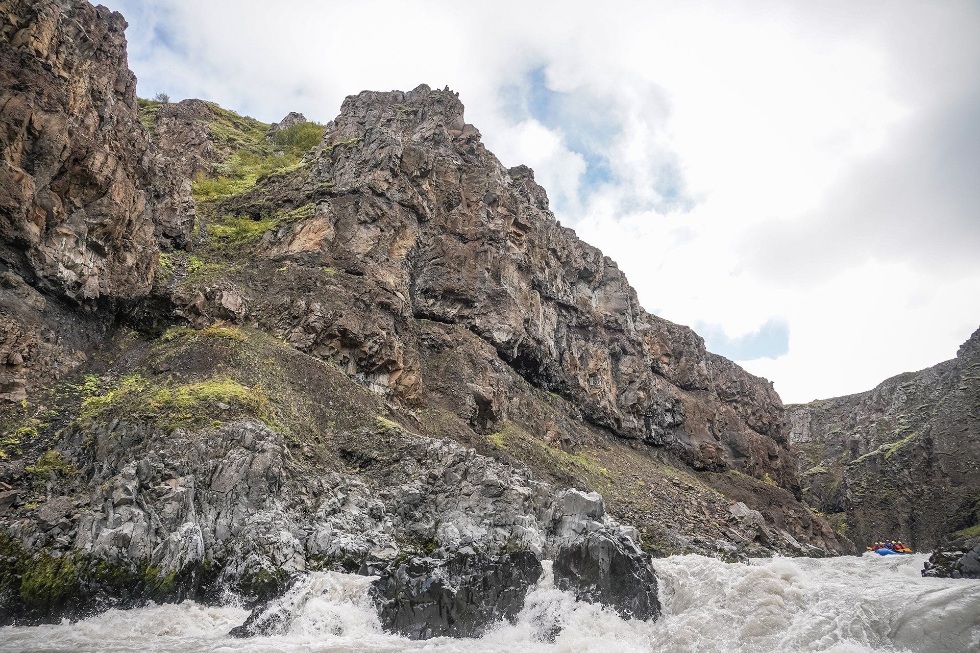 High dark rock walls above the Austari-Jökulsá river with rafts small in the canyon below.