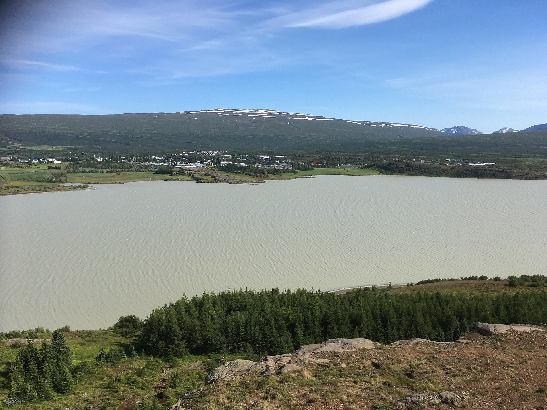 Egilsstaðir beside Lagarfljót with green hills and mountains behind the East Iceland town.