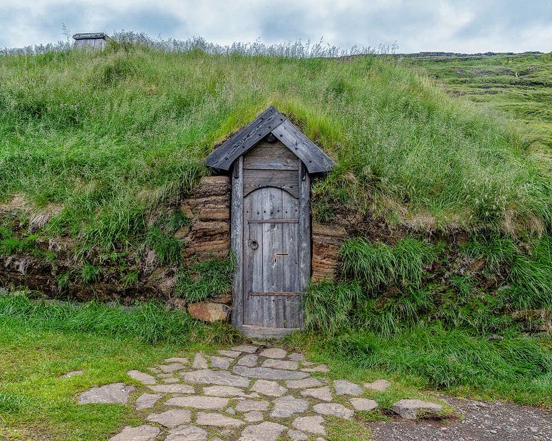 Close view of the wooden door and turf wall at Eiríksstaðir Viking Longhouse.