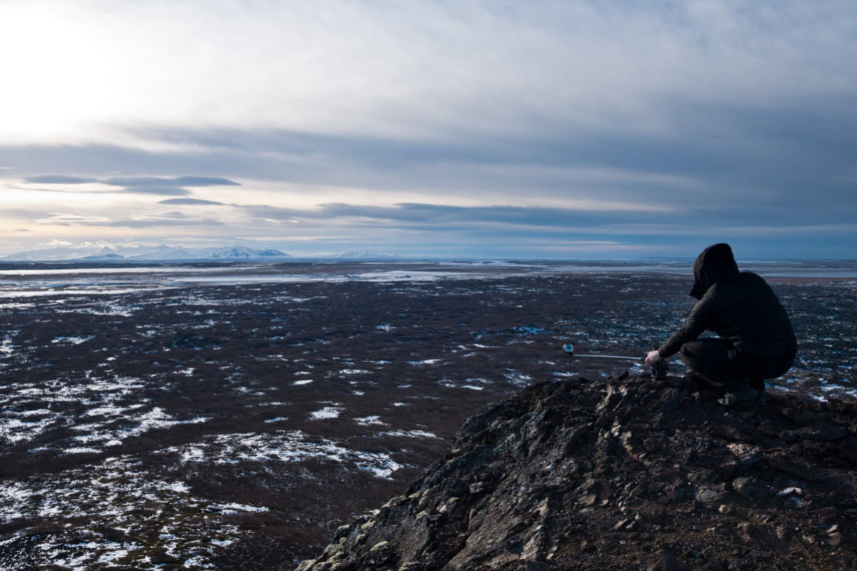 View from the rim of Eldborg crater across dark lava fields and distant West Iceland mountains.