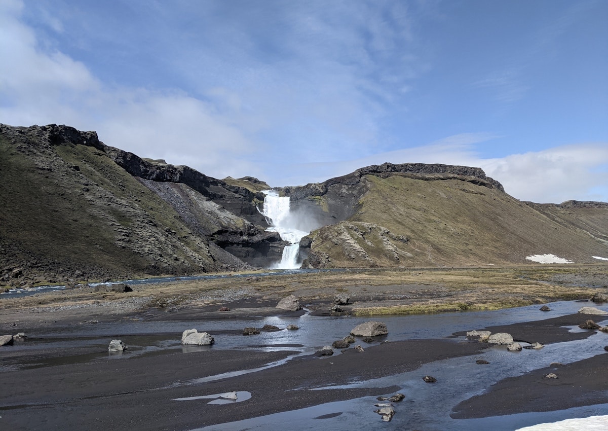 Ófærufoss waterfall seen across dark gravel and pools during thaw conditions in Eldgjá.