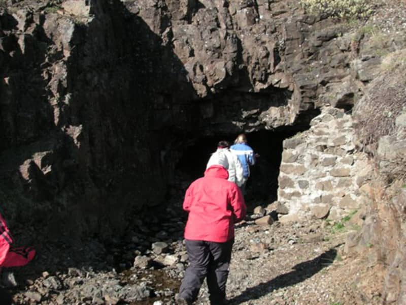 Walkers entering a rocky opening on the Helgustaðanáma trail near Eskifjörður.