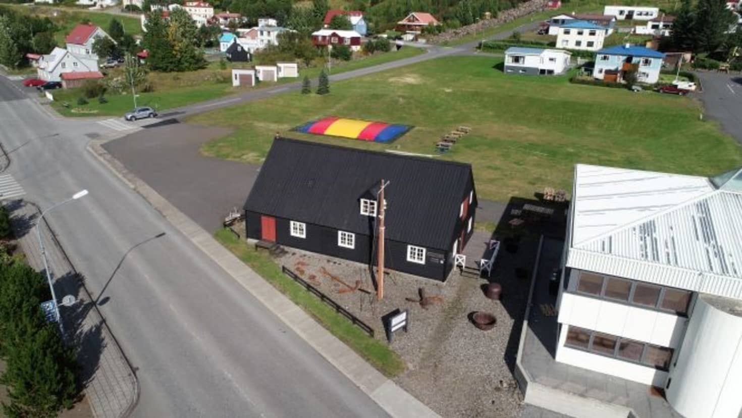 Black timber maritime museum building beside a road in Eskifjörður town.