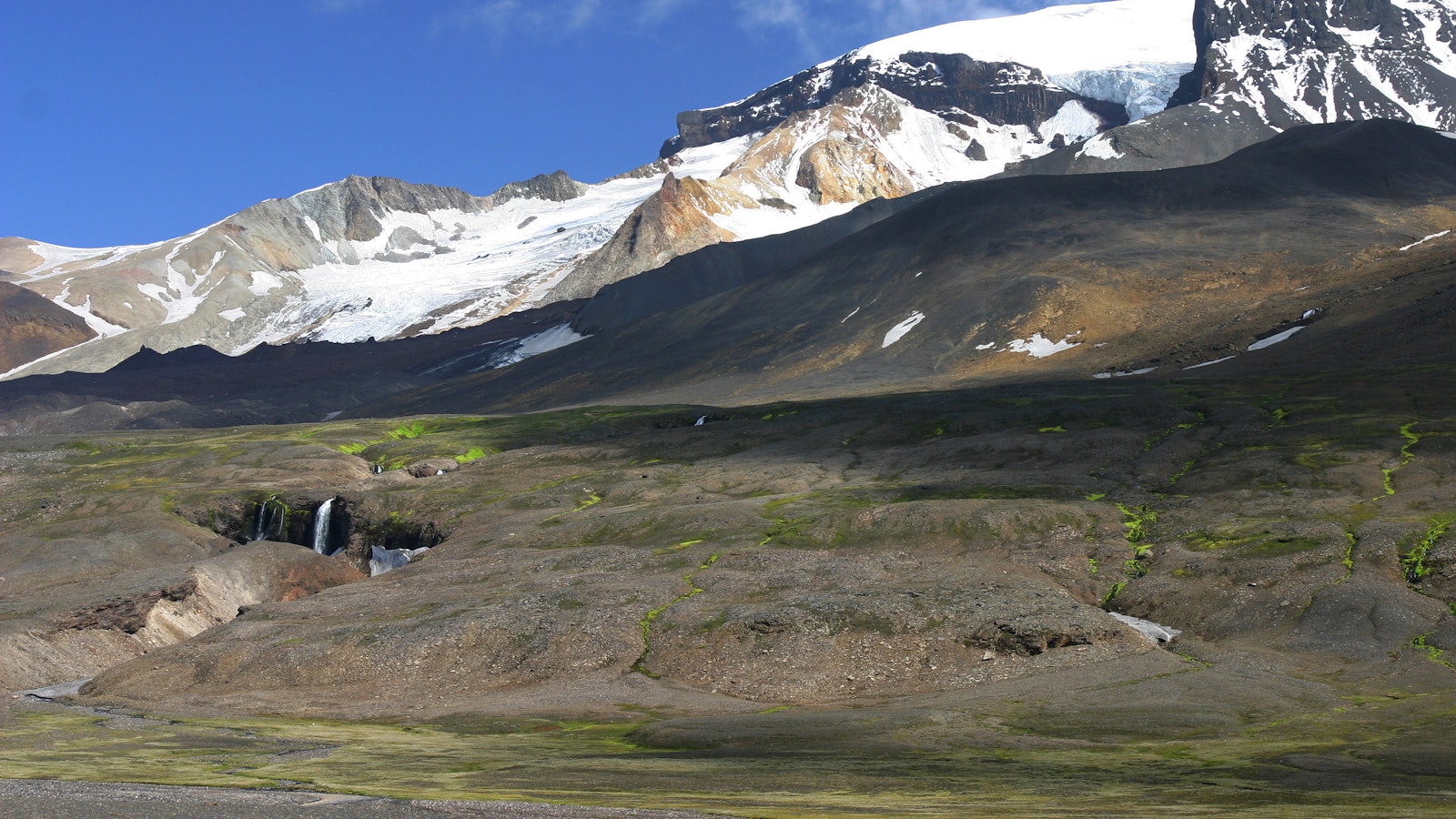 Glacier, waterfall, and dark highland slopes in the Snæfell area near Eyjabakkar.
