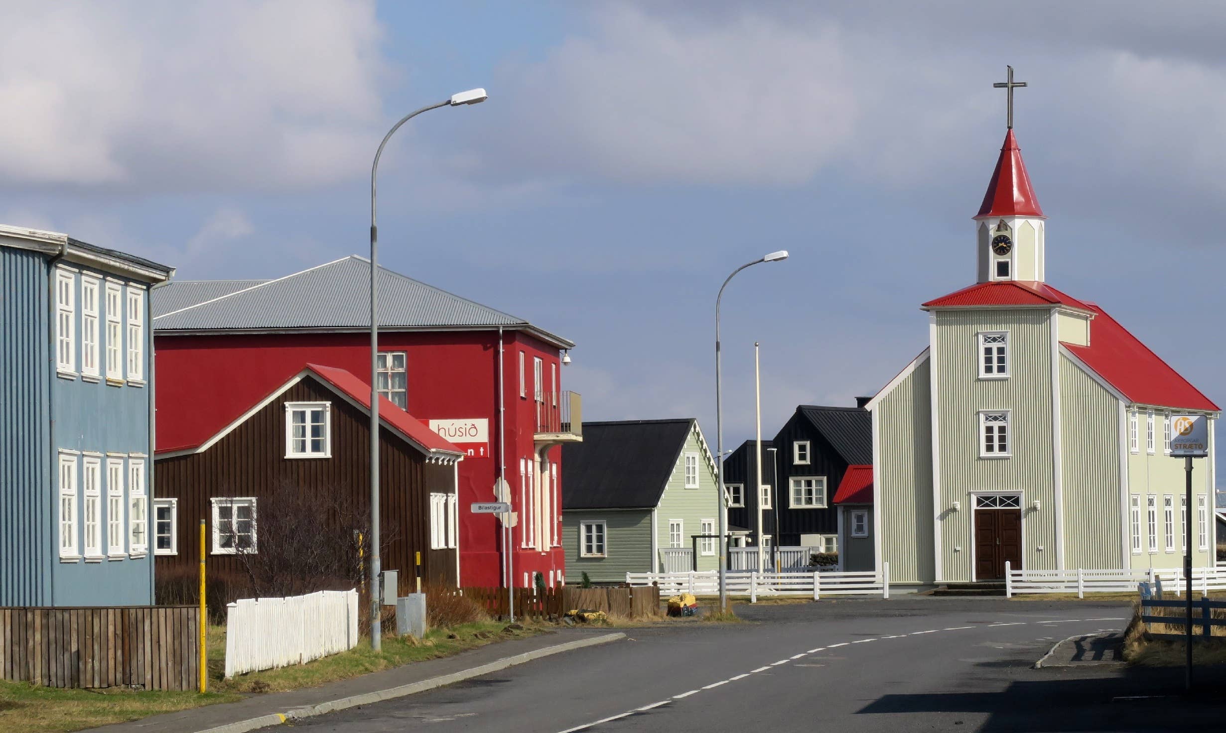 Colorful historic houses and Eyrarbakki church along a quiet village street in South Iceland.