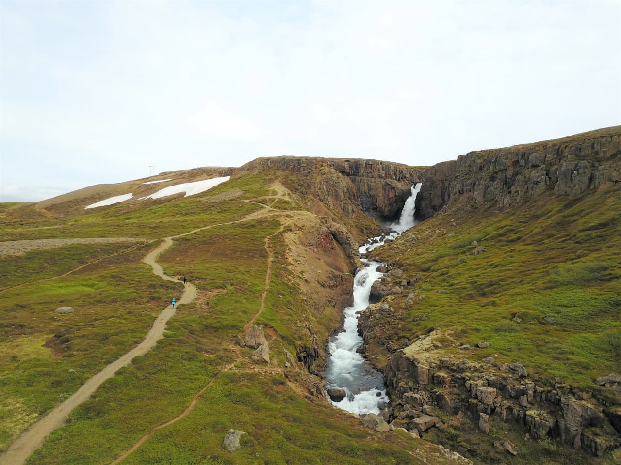 The uphill path leading toward Fardagafoss Waterfall above Egilsstaðir with the ravine and waterfall ahead.