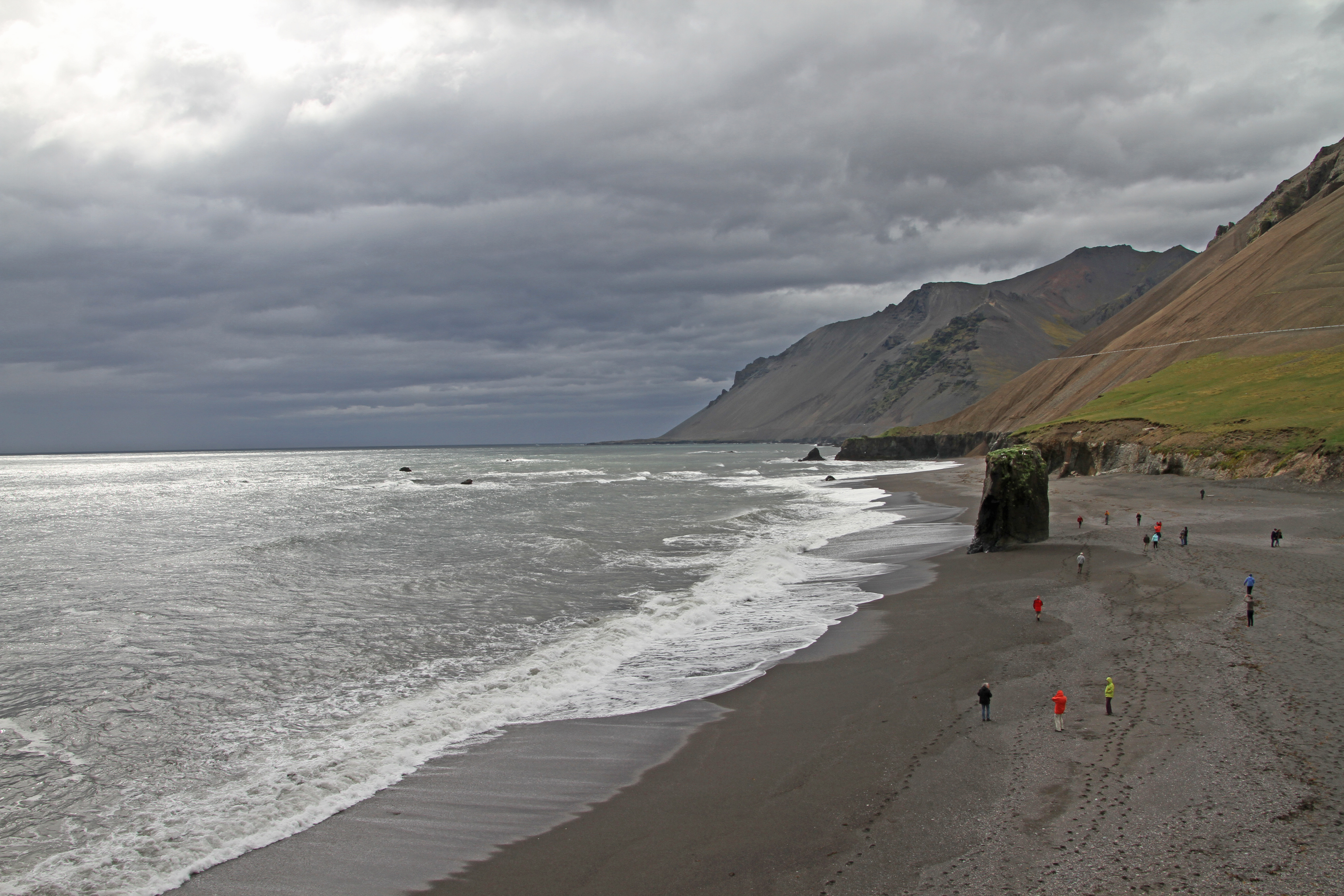 Fauskasandur Black Sand Beach with surf, a sea stack, and steep mountains near Hvalnes in East Iceland.