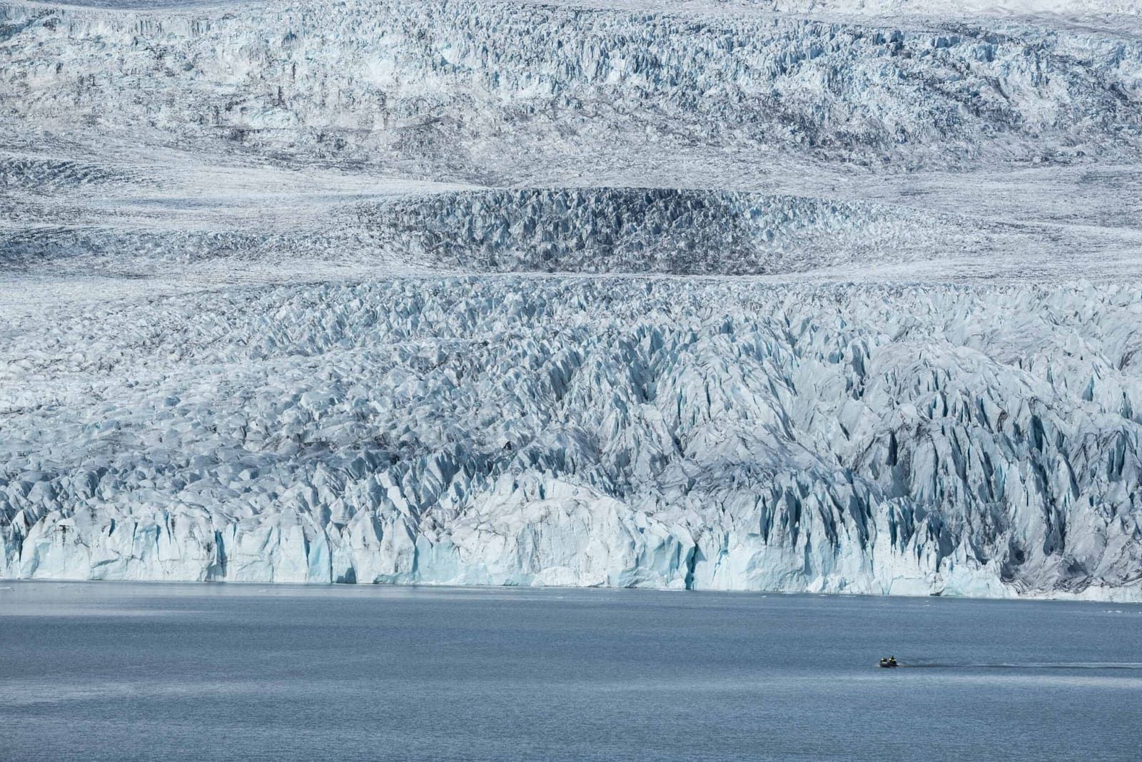 A small boat below the calving front of Fjallsjökull glacier at Fjallsárlón.