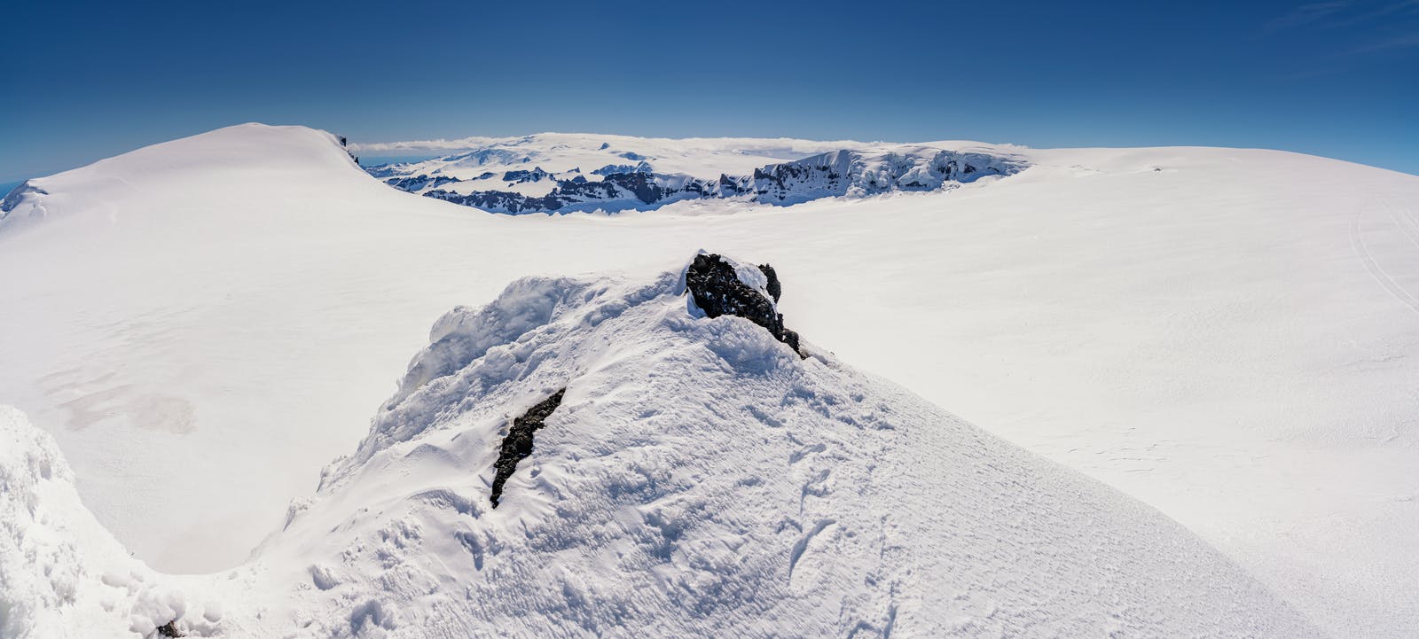 Snow-covered upper glacier and dark volcanic ridges above Fjallsjökull in southeast Iceland.
