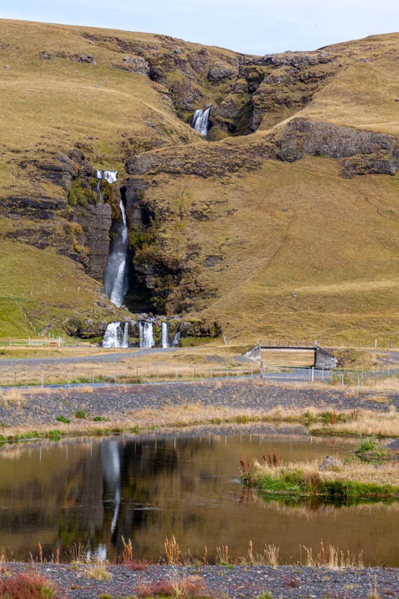 Gluggafoss waterfall dropping through brown hills in the Fljótshlíð area.