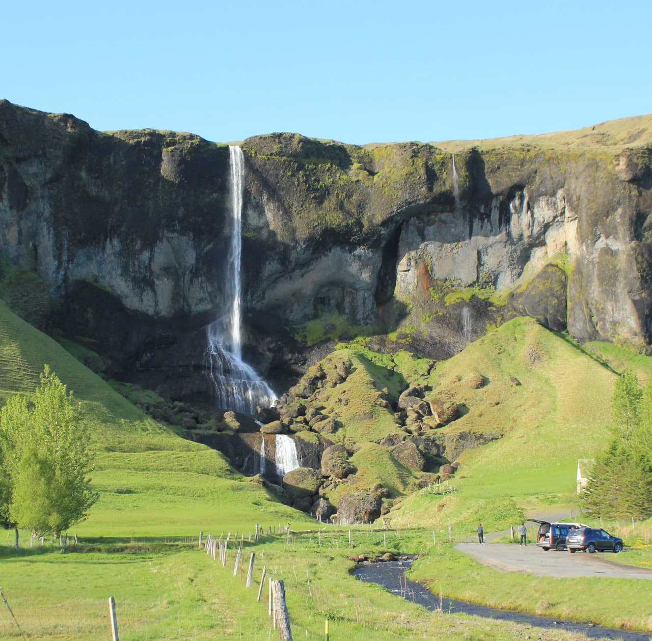 Foss á Síðu falling over green cliffs above farm fields in South Iceland.