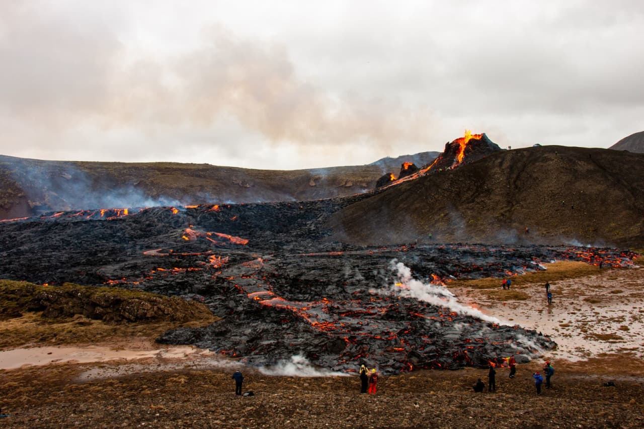 Glowing lava running through the Geldingadalur eruption valley beneath dark Reykjanes ridges.