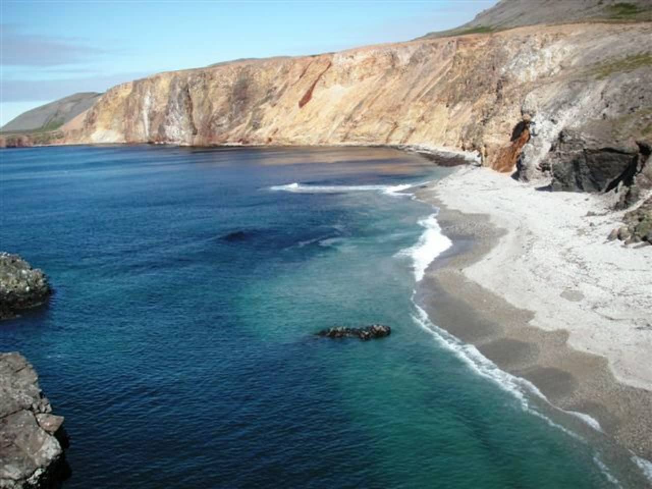 Steep Gerpir cliffs and bright Vöðlavík-area water on the remote East Iceland coast.