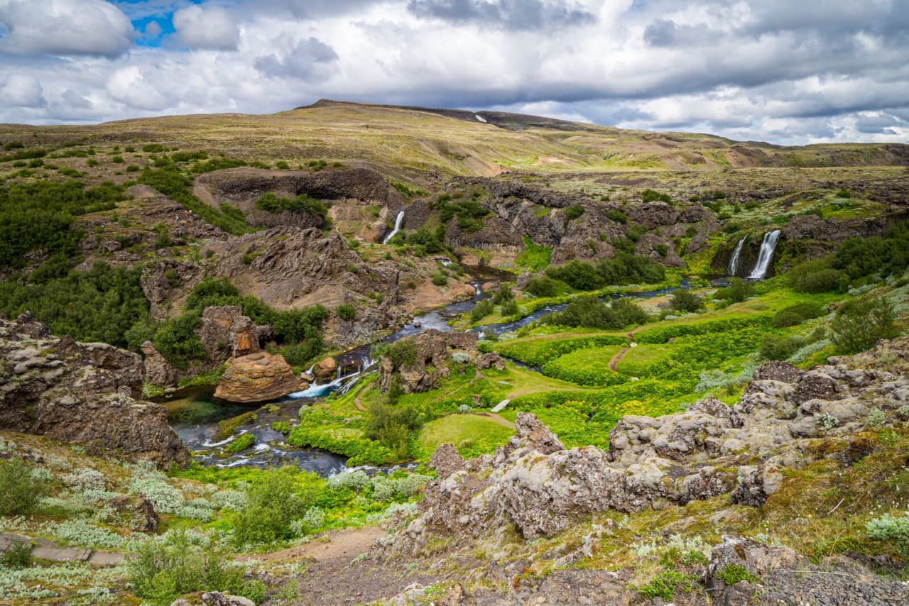 Wide view over Gjáin gorge, waterfalls, and green pools in inland South Iceland.