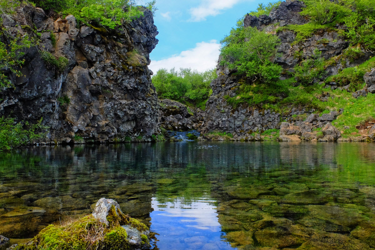 Clear water and green moss between lava walls at Paradísarlaut near Glanni Waterfall.